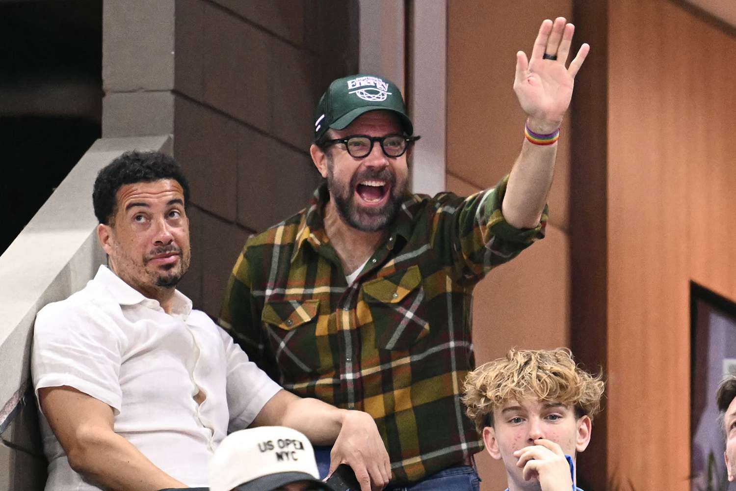 US actor and writer Jason Sudeikis (2nd L) waves as he attends the women's singles round of 16 match between Poland's Iga Swiatek and Russia's Liudmila Samsonova on day eight of the US Open tennis tournament at the USTA Billie Jean King National Tennis Center in New York City, on September 2, 2024.