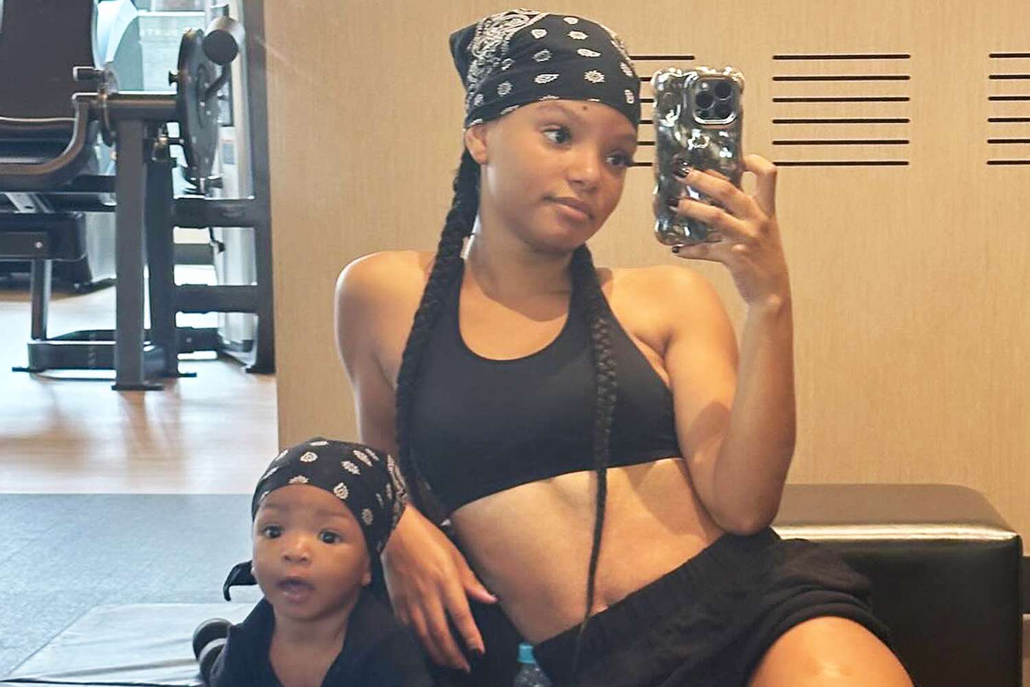 Halle Bailey poses in a mirror selfie with baby in matching bandanas at the gym