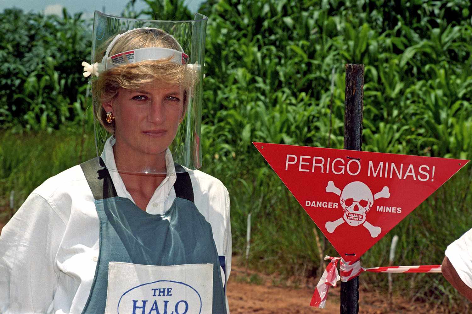 January 15, 1997: DIANA, PRINCESS OF WALES, WEARS A PROTECTIVE MASK AND JACKET AS SHE STANDS NEXT TO A WARNING SIGN ON THE EDGE OF A MINEFIELD IN ANGOLA, DURING HER VISIT TO SEE THE WORK OF THE BRITISH RED CROSS.