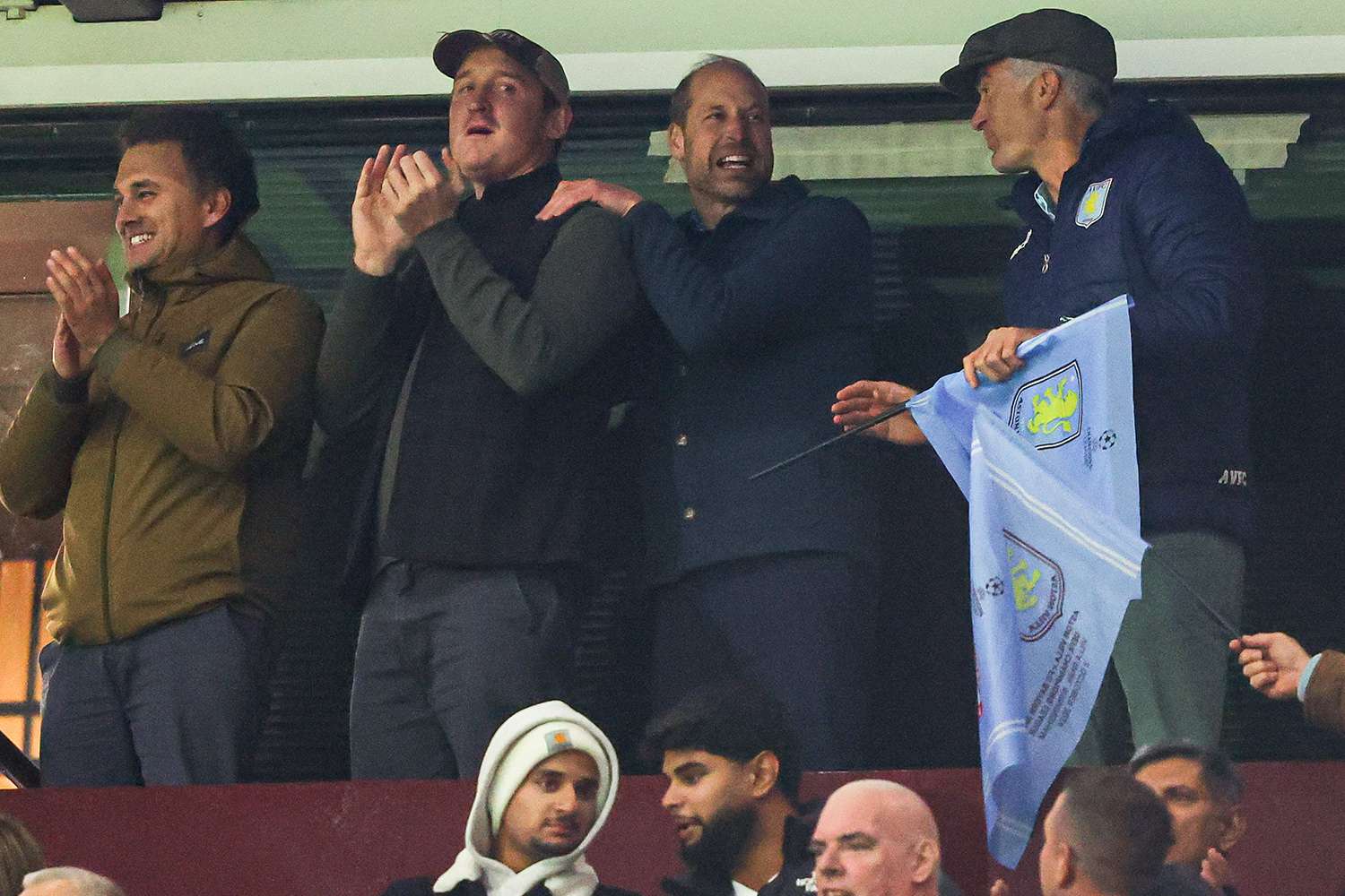 HRH William, Prince of Wales, celebrates Aston Villa's victory with Harry Aubrey-Fletcher (R), Edward van Cutsem (M-L), and Thomas van Straubenzee (L) - childhood friends of Prince William and godparents to his children - on the final whistle during the UEFA Champions League 2024/25 League Phase MD2 match between Aston Villa FC and FC Bayern