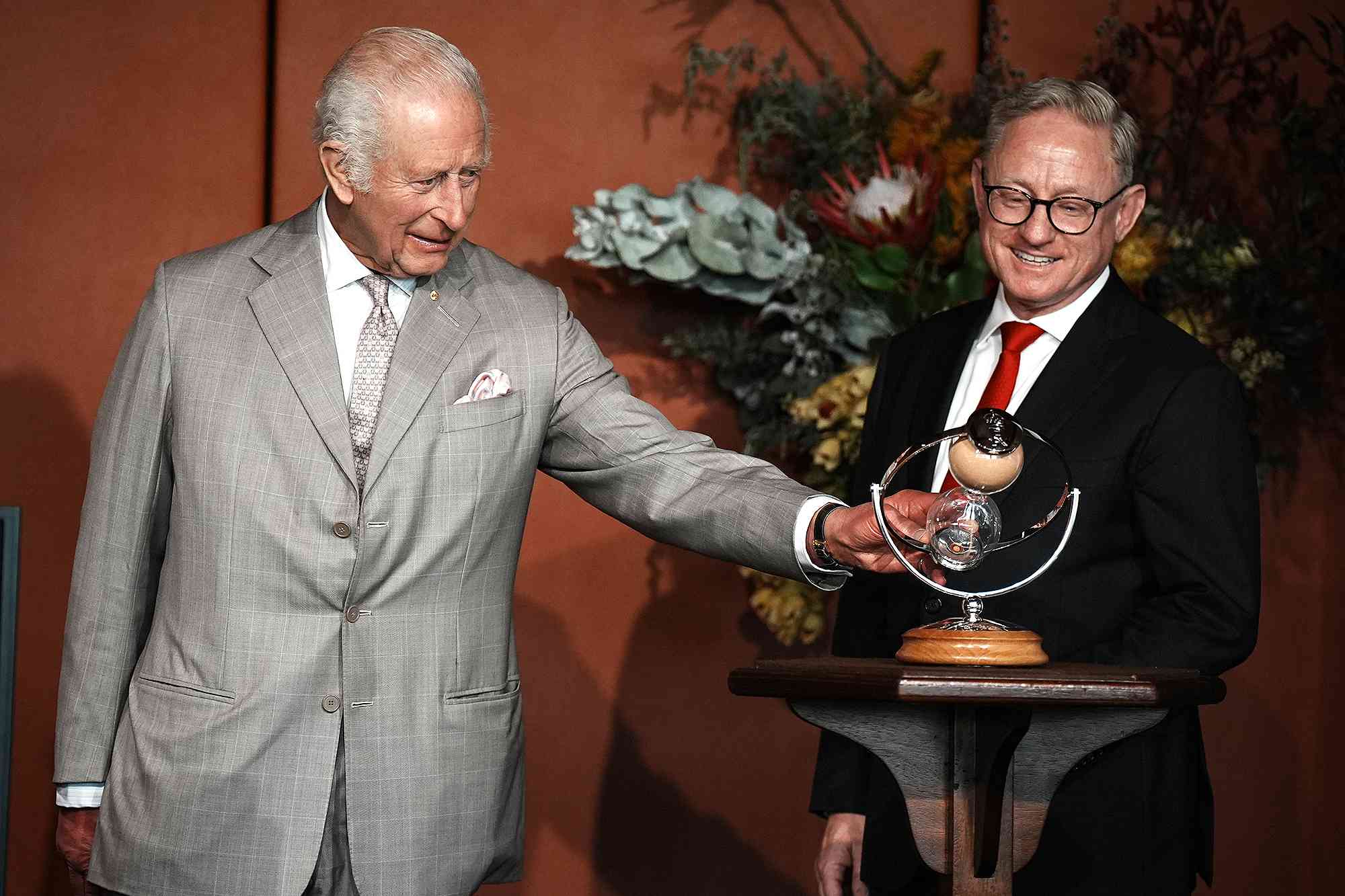 SYDNEY, AUSTRALIA - OCTOBER 20: President of the Legislative Council, Ben Franklin (right), watches as King Charles III turns an hourglass he is presenting as a gift to mark the Bicentenary of the New South Wales Legislative Council, during an event marking the anniversary at New South Wales Parliament House, on October 20, 2024 in Sydney, Australia. The King's visit to Australia will be his first as Monarch, and CHOGM in Samoa will be his first as Head of the Commonwealth. 