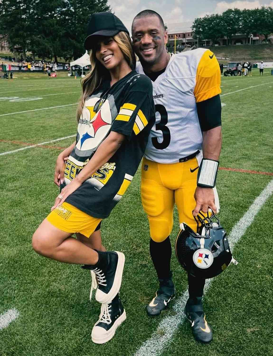 Ciara and Russ Wilson pose together on a football field