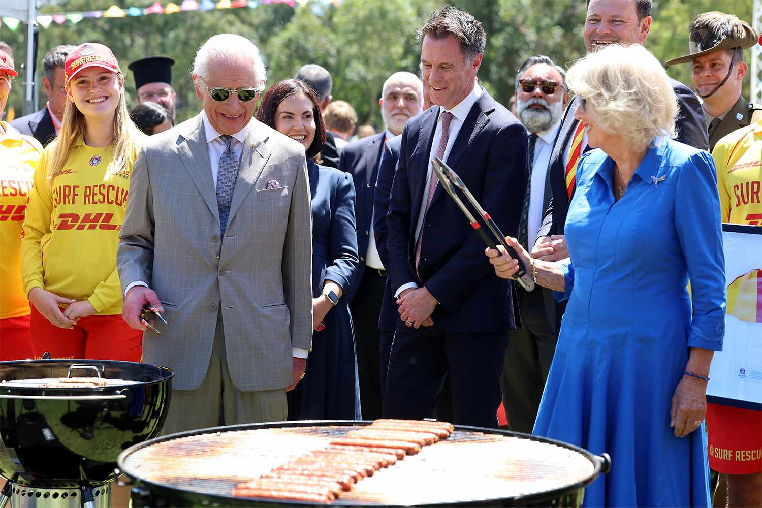 King Charles III and Queen Camilla cook sausages for the food stalls at the Premier's Community Barbeque at Parramatta Park on October 22, 2024 in Sydney, Australia