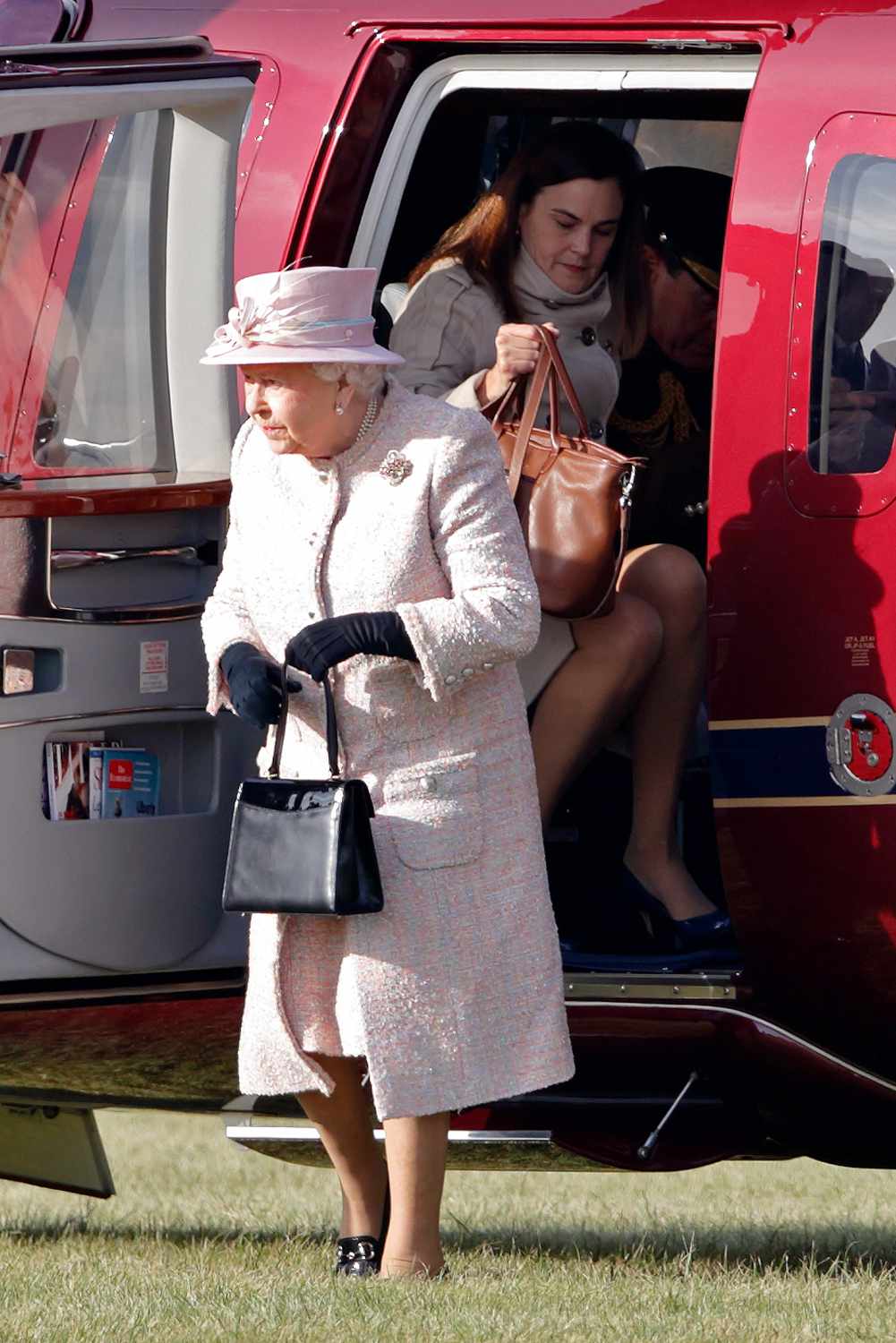 Queen Elizabeth II (accompanied by her Assistant Private Secretary Samantha Cohen) disembarks her Sikorsky Helicopter (The Queen's Helicopter Flight) as she arrives to unveil a statue depicting herself alongside a mare and it's foal in 1977 on November 3, 2016 in Newmarket, England.