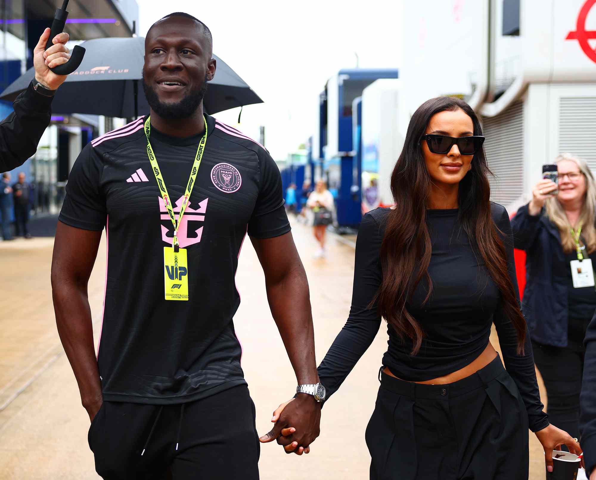 Stormzy and Maya Jama walk in the Paddock after practice ahead of the F1 Grand Prix of Great Britain at Silverstone Circuit on July 05, 2024 in Northampton, England.