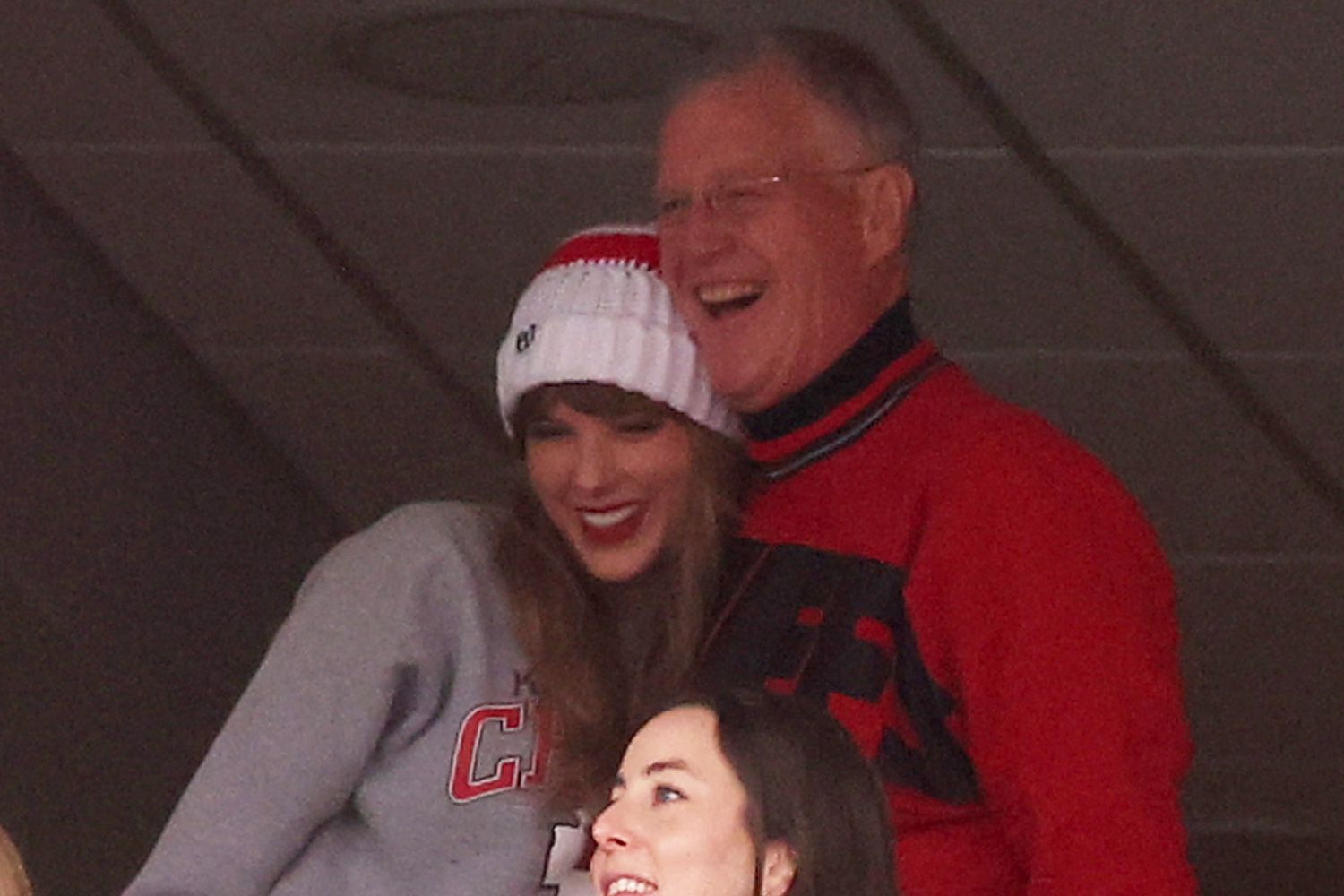 Brittany Mahomes looks on while Taylor Swift hugs Scott Kingsley