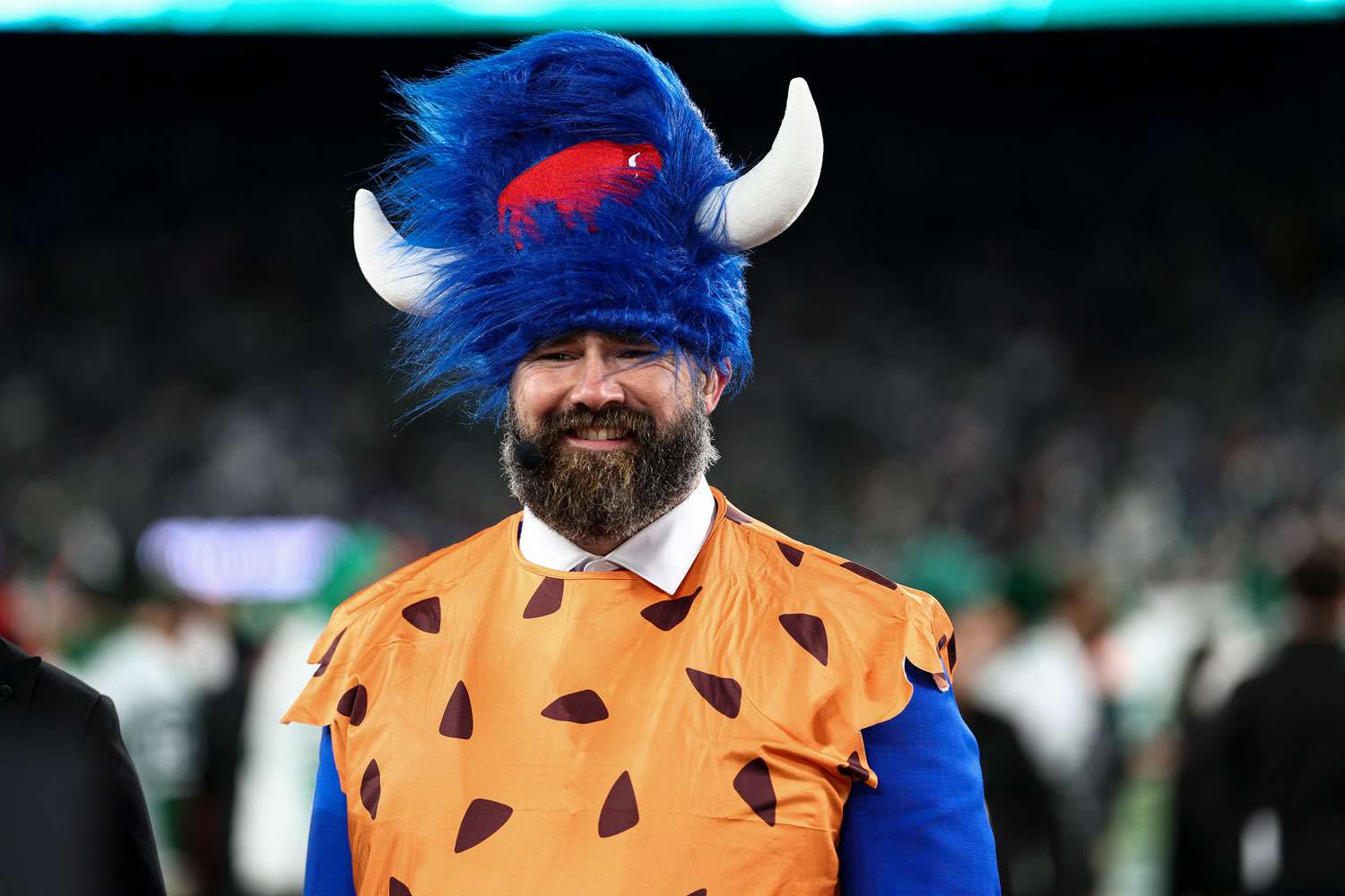 ESPN broadcaster Jason Kelce smiles on the field wearing a Buffalo Bills and Flinstones costume prior to an NFL game between the New York Jets and the Buffalo Bills at MetLife Stadium on October 14, 2024