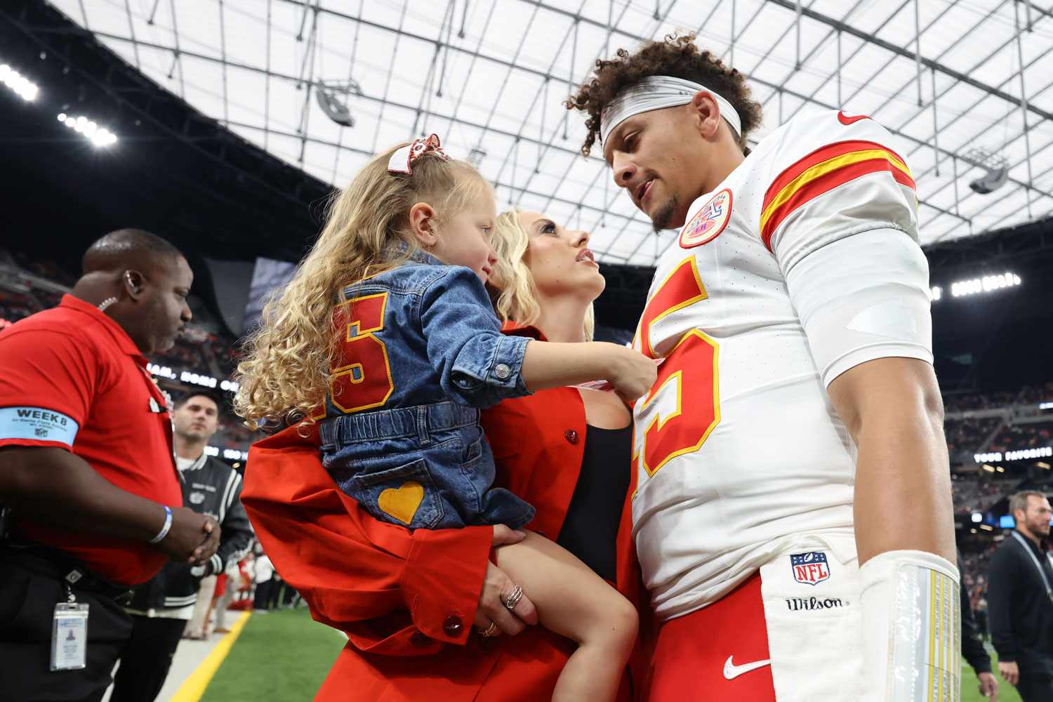 Patrick Mahomes of the Kansas City Chiefs kisses his wife, Brittany, while their daughter, Sterling, watches prior to a game against the Las Vegas Raiders at Allegiant Stadium on October 27, 2024