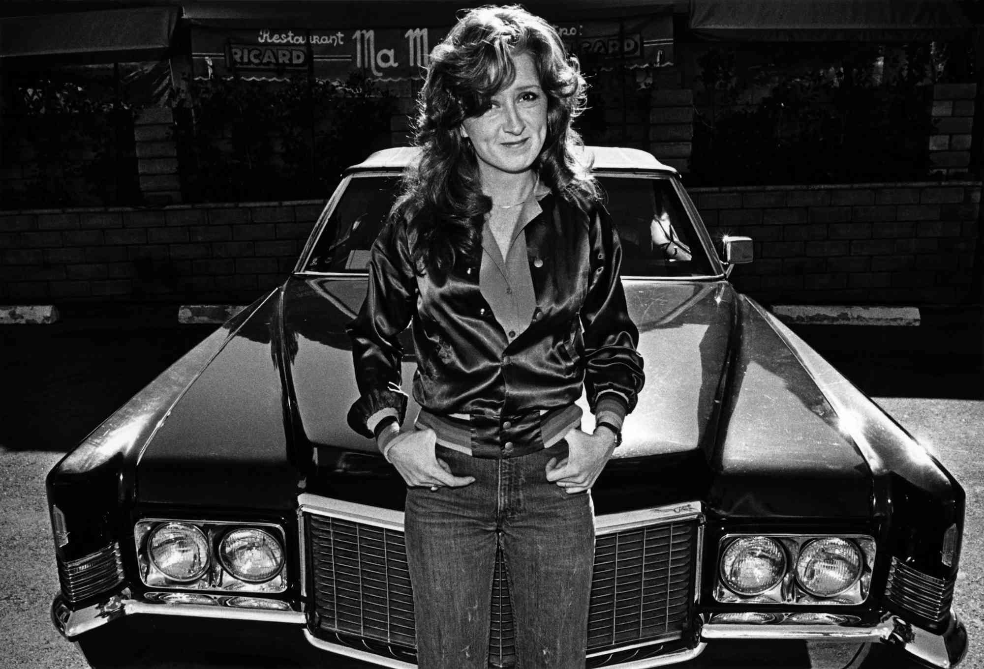 Singer/songwriter Bonnie Raitt sits on the hood of a car as she poses for a 1980 portrait outside Ma Maison restaurant in West Hollywood, California. The daughter of Broadway singer John Raitt, Bonnie made her name singing blues-tinged rock ballads. 