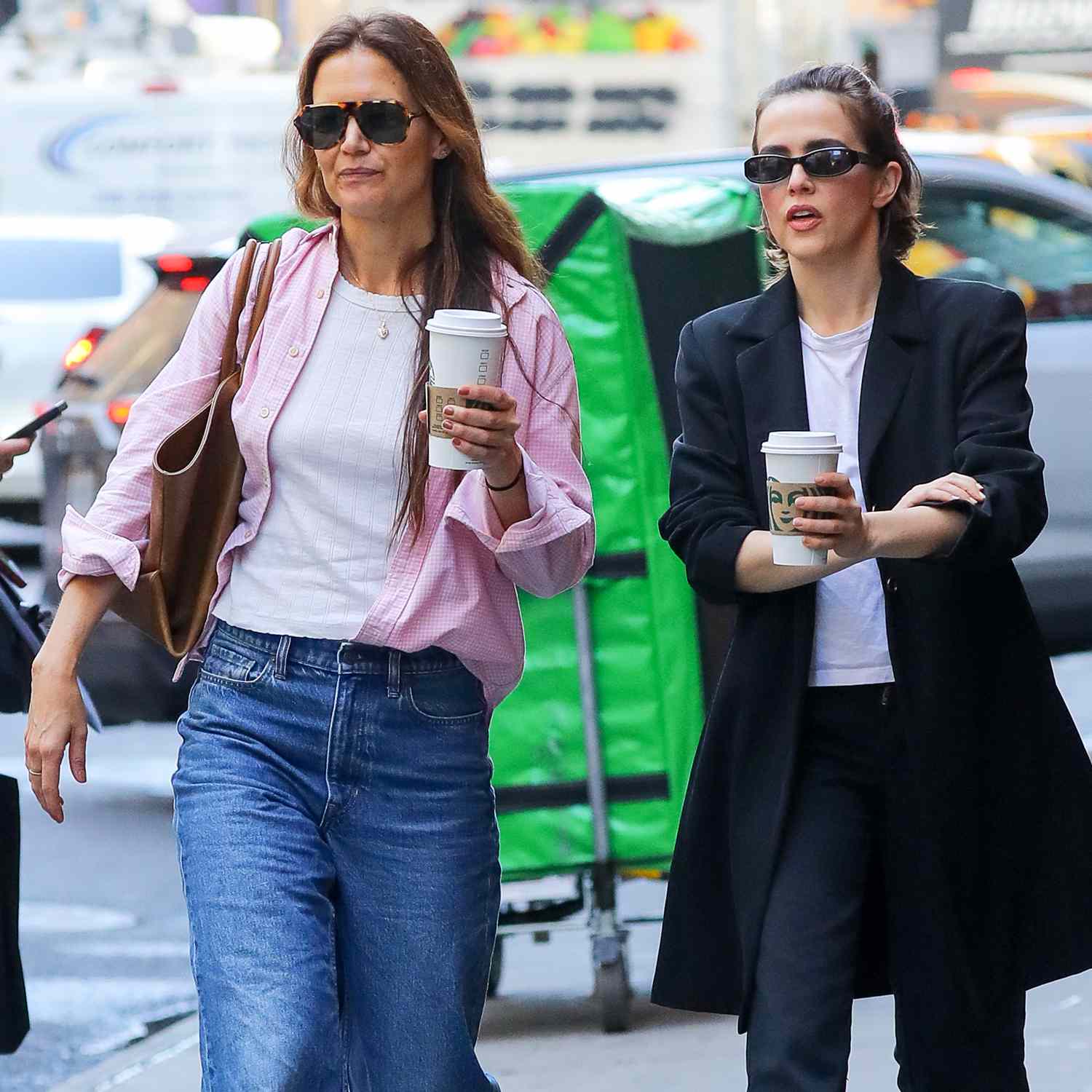 Katie Holmes and Zoey Deutch go for a coffee run in New York City. Katie carried a brown Khaite envelope pleat tote and wore a pink 