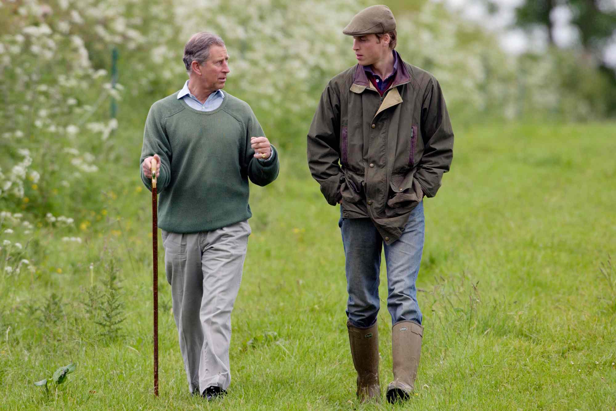 Prince William, In Countryman Outfit Of Tweed Cap And Waxed Jacket And With His Hands In His Pockets, Visits Duchy Home Farm With Prince Charles Who Is Holding A Shepherd's Crook Walking Stick