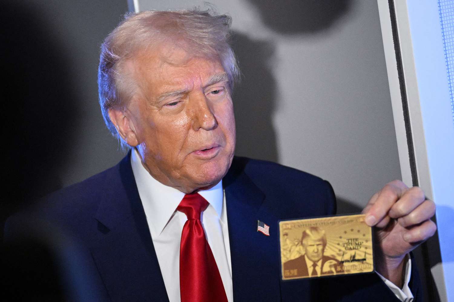 US President Donald Trump holds the $5 million dollar Gold Card as he speaks to reporters while in flight on board Air Force One, en route to Miami, Florida on April 3, 2025